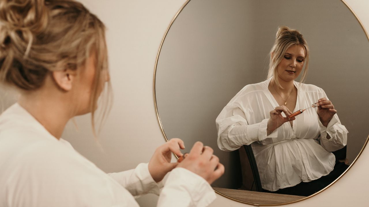 Swift Current Makeup artist Indianna opens lip gloss in the mirror during a brand photography session