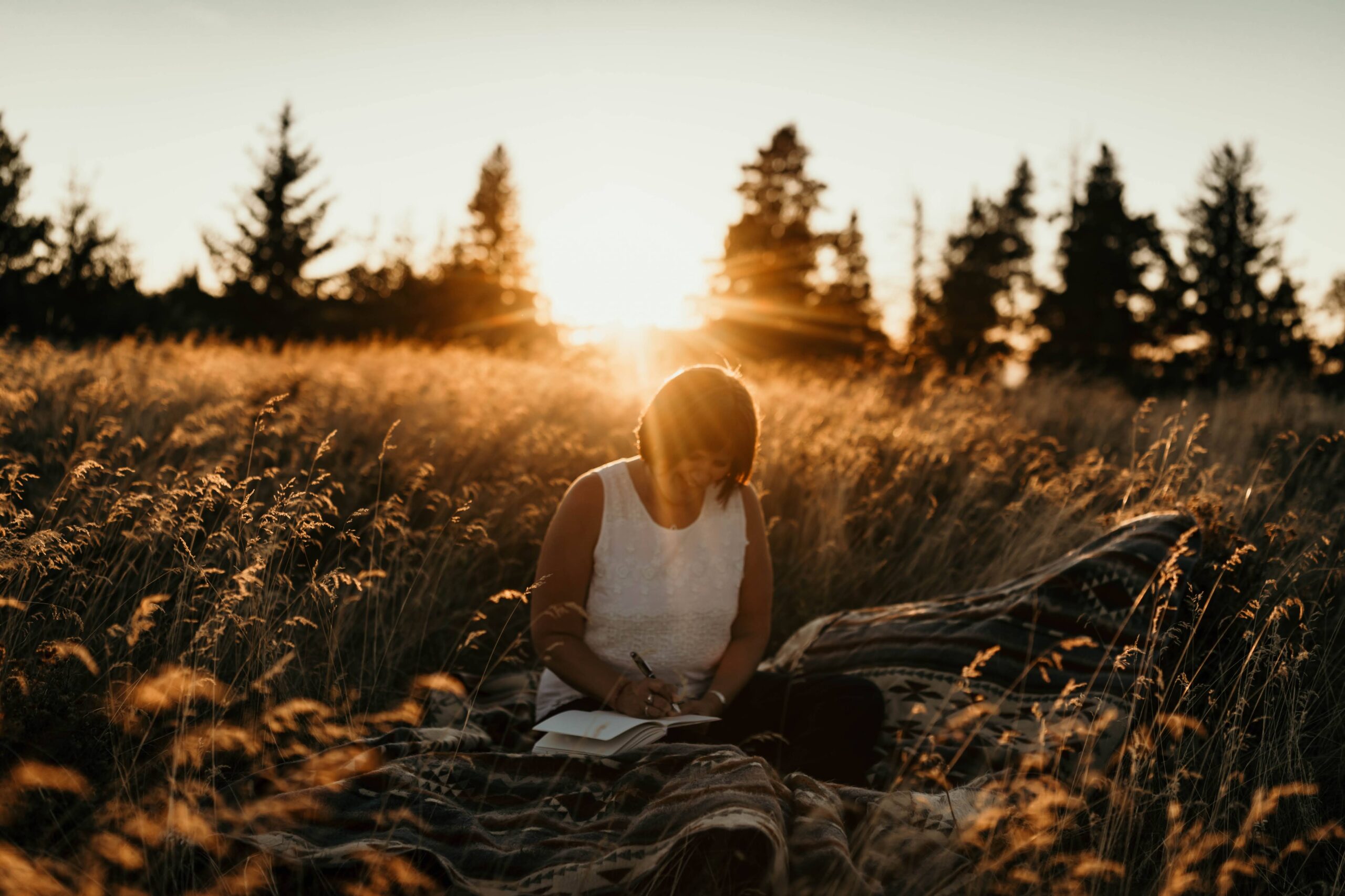 author writing in a prairie field in cypress hills saskatchewan during a brand photography session.