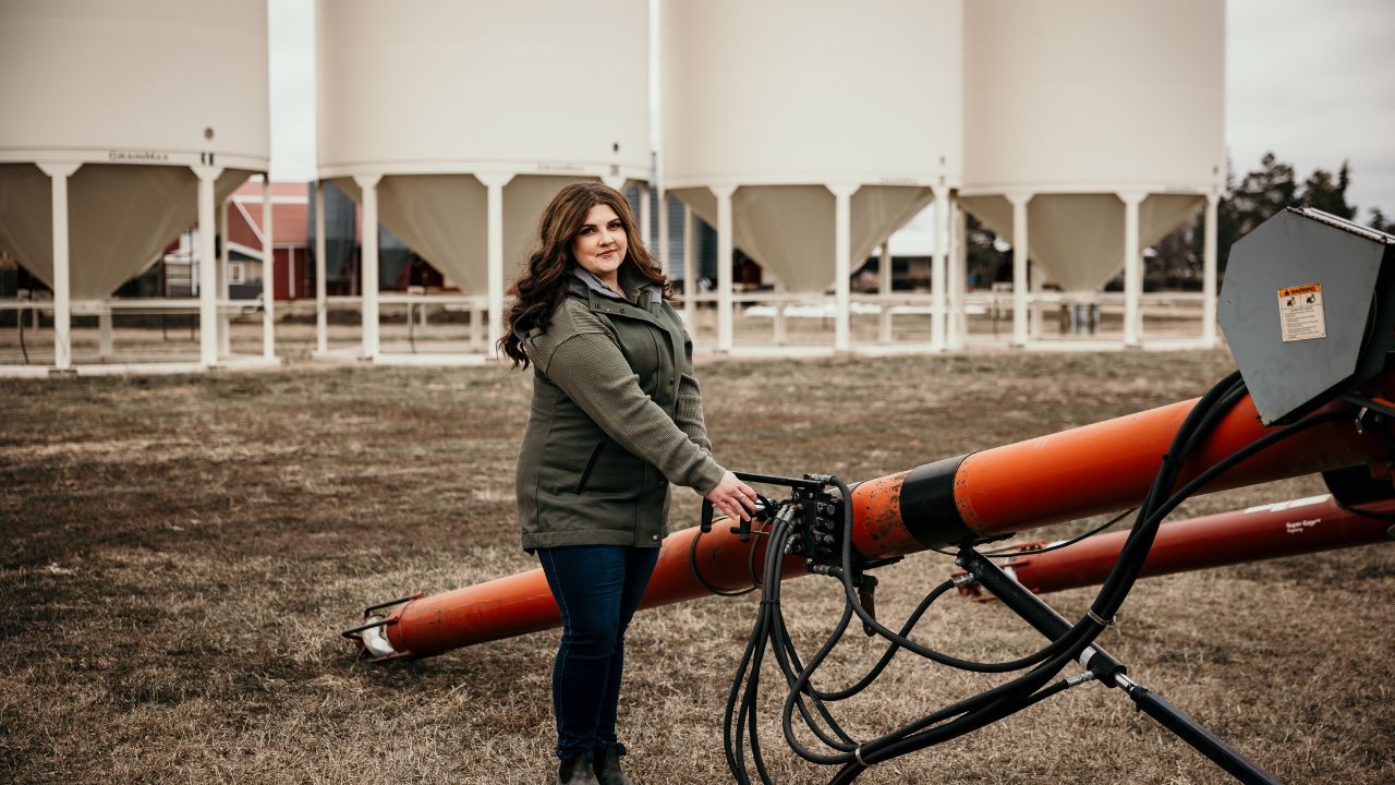 woman moves auger around grain bins during brand photography session