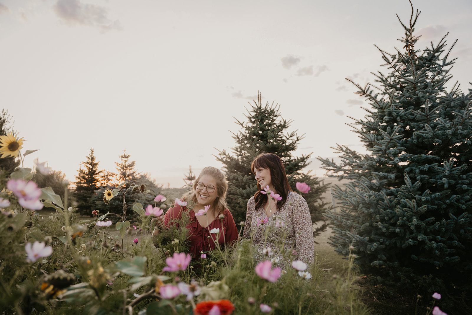 Flower farmer sisters look at flowers in their garden during a brand photography photo session